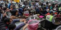 Palestinos tentam alcançar alimentos distribuídos por voluntários em Rafah, na Faixa de Gaza  Foto: DW / Deutsche Welle