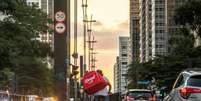 Entregador do aplicativo iFood atravessa a Avenida Paulista, em São Paulo.  Foto: Daniel Teixeira/Estadão / Estadão