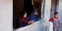 Palestinos olham destruição por janela de casa  Foto: Reuters / BBC News Brasil