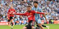 Foto: Glyn Kirk / AFP via Getty Images - Legenda: Bruno Fernandes chuta para fazer o terceiro gol do United contra o Coventry, pela Copa da Inglaterra / Jogada10
