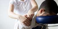 Homem recebe shiatsu na cadeira da massagem  Foto: Alice Gaudioso/iStock