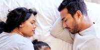 Imagem meramente ilustrativa de pais compartilhando a cama com uma bebê  Foto: PeopleImages/iStock