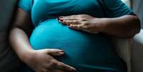 Mulher grávida tocando sua barriga  Foto: FG Trade/iStock