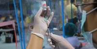 Mão segurando seringa e retirando líquido de frasco de vacina  Foto: Getty Images / BBC News Brasil