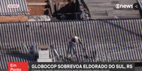 TV flagrou resgate de mulher e cachorro ilhados em cima de telhado   Foto: Reprodução/GloboNews