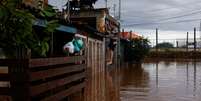 Homem escala portão de casa em Eldorado, Rio Grande do Sul, em meio à enchente  Foto: REUTERS/Amanda Perobelli