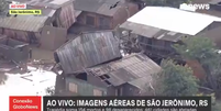 Casa de madeira vai parar em cima de outro imóvel após ser arrastada pelas chuvas  Foto: Reprodução/Globo News