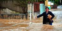 Homem resgatando um cachorro na inundação  Foto: cabuscaa/iStock