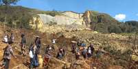 Pessoas em torno de área onde ocorreu deslizamento  Foto: Getty Images / BBC News Brasil