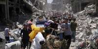 A group of Palestinians surrounded by destroyed buildings  Foto: Reuters / BBC News Brasil