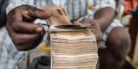 Homem manipula grande maço de notas de naira  Foto: Getty Images / BBC News Brasil