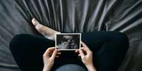 Uma pessoa grávida, segurando imagem de ultrassom.   Foto: d3sign / Getty Images