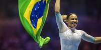 Rebecca Andrade comemora com a bandeira brasileira após conquistar a medalha de ouro durante a final individual individual feminina no Campeonato Mundial de Ginástica-Liverpool 2022.   Foto: Tim Clayton/Corbis via Getty Images