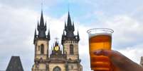 Homem segura copo de cerveja ao longo da cidade de Praga  Foto: BreakingTheWalls/GettyImages