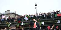 Argelinos com flores durante cerimônia de abertura de Paris-2024  Foto: Annegret Hilse