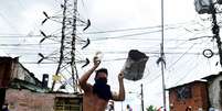 Um homem segura um tanque de metal enquanto moradores batem panelas para protestar contra os resultados das eleições depois que o presidente Nicolás Maduro e seu rival da oposição Edmundo Gonzalez reivindicaram a vitória na eleição presidencial de domingo, no bairro de Los Magallanes de Catia, em Caracas, Venezuela   Foto: REUTERS/Maxwell Briceno