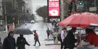 Pedestres enfrentam chuva e frio, com termômetros oscilando entre 16°C e 17°C graus, na manhã desta terça-feira (30/7), próximo à Estação de metrô do Brooklin, na zona sul de São Paulo.  Foto: RENATO S. CERQUEIRA/ATO PRESS/ESTADÃO CONTEÚDO