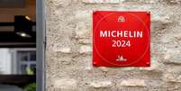 A foto mostra uma parede com uma placa vermelha escrito em branco "Michelin 2024".   Foto: Alamy / BBC News Brasil