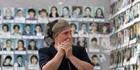 Mulher chorando ao ver as fotos das vítimas do ataque no ginásio da escola de Beslan.  Foto: Getty Images / BBC News Brasil