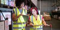 Duas mulheres, com coletes, trabalham em um centro de distribuição  Foto: Getty Images / BBC News Brasil