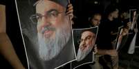 Apoiadores do líder do Hezbollah, Hassan Nasrallah, carregam suas fotografias enquanto se reúnem em Sidon, no Líbano, após sua morte.  Foto: Reuters / BBC News Brasil