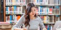 Mulher estudando em biblioteca.   Foto: TZIDO SUN | Shutterstock / Portal EdiCase