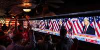 Apoiadores do candidato presidencial republicano, ex-presidente dos EUA, Donald Trump, reagem ao lado de telas que mostram Trump falando no Centro de Convenções do Condado de Palm Beach, enquanto participam da festa de observação do New York Young Republican Club durante a eleição presidencial dos EUA de 2024, em Manhattan, Nova York, EUA, 6 de novembro de 2024.   Foto: REUTERS/Andrew Kelly