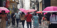 Pedestres se protegem da chuva na região central de São Paulo, na tarde desta quarta- feira (6).  Foto: CRIS FAGA/DRAGONFLY PRESS/ESTADÃO CONTEÚDO