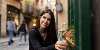 Mulher italiana sorrindo e comprando alimento na cidade.  Foto: Freepik