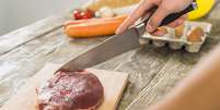 Homem usando tábua de corte para preparar carne vermelha.  Foto: Freepik