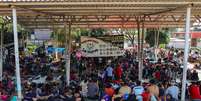 Migrantes aguardam em uma quadra de esportes por caravana com destino à fronteira norte entre Estados Unidos e México, na cidade de Huixtla  Foto: REUTERS/Raquel Cunha
