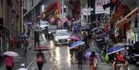 Pedestres enfrentam chuva no cruzamento da Ladeira Porto Geral com a rua 25 de Março, região de comércio popular no Centro de São Paulo, na tarde desta quinta-feira, 3.  Foto: CRIS FAGA/DRAGONFLY PRESS/ESTADÃO CONTEÚDO