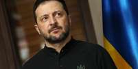 Presidente Volodymyr Zelensky ao lado da bandeira da Ucrânia  Foto: Getty Images / BBC News Brasil