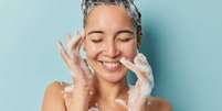 Veja as energias que combinam com seu signo - Foto: Shutterstock  Foto: imagem do rosto de uma mulher jovem tomando banho com o cabelo ensaboado em fundo azul / João Bidu - Terra Astral