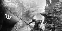 Soldados do Exército Vermelho hasteando a bandeira soviética no Reichstag em Berlim, Alemanha, 30 de abril de 1945, foto tirada por Vladimir Grebnev.  Foto: Getty Images / BBC News Brasil
