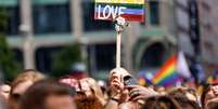 Um participante segura uma placa com os dizeres "Love is Love" durante o protesto do 44º Christopher Street Day (CSD) durante o Mês do Orgulho em Berlim, 23 de julho de 2022.  Foto: AFP - DAVID GANNON / RFI