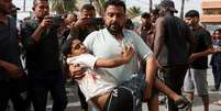 Homem carrega criança ferida até hospital na Faixa de Gaza após novo ataque de Israel  Foto: Reuters / BBC News Brasil