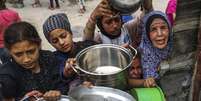 Palestinos, lutando contra a fome devido ao bloqueio israelense, esperam na fila com panelas vazias nas m&atilde;os para receber refei&ccedil;&otilde;es distribu&iacute;das por organiza&ccedil;&otilde;es humanit&aacute;rias em Gaza, em 17 de maio de 2025  Foto: Getty Images / BBC News Brasil