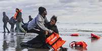 Foto ilustrativa: Um migrante sudanês na areia após deixar o barco de um traficante, que foi esvaziado por policiais franceses para impedir a travessia da Mancha. A cena aconteceu na praia de Gravelines, perto de Dunkerque, no norte da França, em 26 de abril de 2024.  Foto: AFP - SAMEER AL-DOUMY / RFI