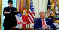 Donald Trump sentado e Elon Musk, de p&eacute;, na Casa Branca  Foto: Reuters / BBC News Brasil