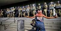 Manifestante se posiciona diante de barreira das forças de segurança durante protesto em Los Angeles na segunda-feira (9).  Foto: AP - Eric Thayer / RFI