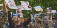 Pessoas mostram fotos de seus parentes desaparecidos a soldados ucranianos na região de Chernihiv, na Ucrânia, que retornam após uma troca de prisioneiros de guerra entre Rússia e Ucrânia.  Foto: AP - Efrem Lukatsky / RFI