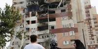 Pessoas observam um prédio danificado após ataques israelenses em Teerã, no Irã  Foto: Reuters / BBC News Brasil