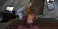Hidaya, palestina de 31 anos, com seu beb&ecirc; de 18 meses em um campo de refugiados em Gaza  Foto: ANSA / Ansa - Brasil