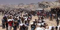 Palestinos carregam sacos de farinha distribu&iacute;dos no norte da Faixa de Gaza ap&oacute;s pausa em combates  Foto: ANSA / Ansa - Brasil