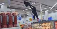 Policial militar subiu em gôndolas do supermercado para tirar homem que estava pendurado no teto  Foto: Reprodução/X