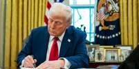 Donald Trump assina ordem executiva na mesa da presidência na Casa Branca  Foto: Bloomberg via Getty Images / BBC News Brasil