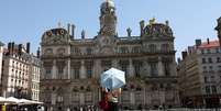 Uma mulher usa uma sombrinha para se proteger do calor em Lyon, no sudeste da França, onde são previstos até 42°C nesta quarta-feira, 13 de agosto de 2025.  Foto: REUTERS - Abdul Saboor / RFI