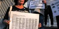 Uma mulher segura um cartaz com os nomes dos jornalistas mortos em conflitos nos territórios palestinos, no Líbano e em Israel desde 7 de outubro de 2023  Foto: AFP - AHMAD GHARABLI / RFI