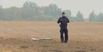 Um policial polonês examina um fragmento de um drone russo em Czesniki, na região de Lublin, na Pologne, em 10 de setembro de 2025.  Foto: © Polsat News via REUTERS / RFI